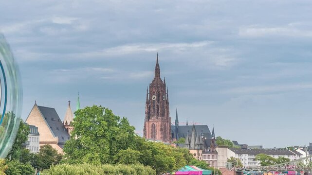 Aerial hyperlapse of pleasure boats on the Rhine Main, framed by the spire of Kaiserdom St. Bartholomaus. Eiserner Steg bridge and Ferris wheel add vibrancy to Frankfurt's scenic waterfront timelapse