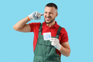 Male worker with speaker icon suffering from loud noise on blue background