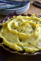 Homemade shepherd’s pie with mashed potatoes and minced meat, served in a cozy rustic kitchen setting. Comforting classic British dish perfect for cozy meals and homestyle food photography.