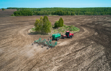 Tractor cultivating a field in springtime across an expansive landscape with clear skies