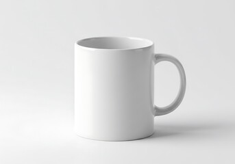 Obraz premium A simple white ceramic mug with a handle sitting on a white surface in a studio setting neutral light
