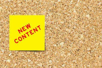 Yellow note paper with word new content on cork board background with copy space