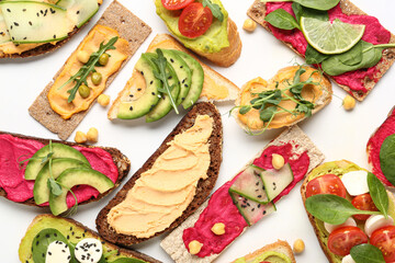 Assortment of different sandwiches with hummus, cheese and vegetables on white background