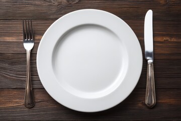 A white plate with a fork and knife on a wooden table, ready for a meal.