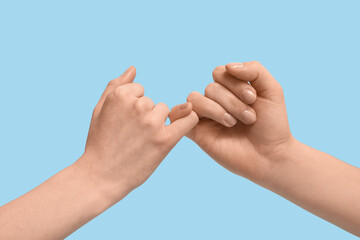 Women making pinkie promise on color background, closeup. Friendship Day celebration