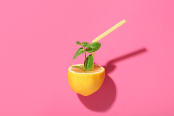Creative composition with half of lemon, mint and straw on color background