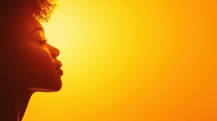 Silhouette of young african female profile against orange background