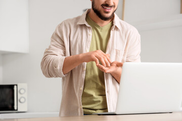 Young mute man using sign language during video call at home