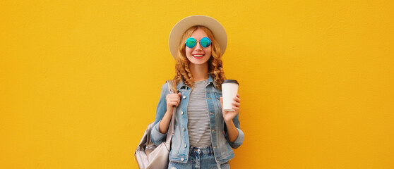 Beautiful stylish happy young woman with cup of coffee wearing summer hat on yellow background