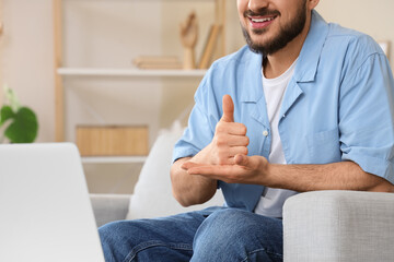 Young mute man using sign language during video call at home