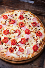 Pizza with ham, cherry tomatoes and mozzarella cheese. Wooden background. Soft focus. Close up.	