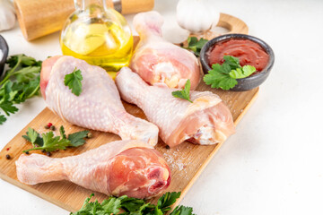 Chicken meat preparation background, raw chicken legs ready for grilling, with spices, salt, pepper, olive oil, garlic and marinade or sauce. Grilll and bbq season cooking background, copy space