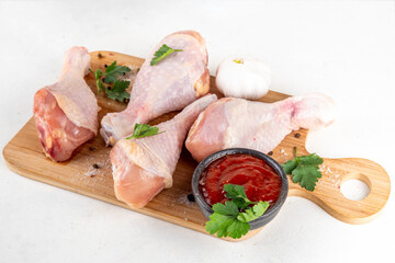 Chicken meat preparation background, raw chicken legs ready for grilling, with spices, salt, pepper, olive oil, garlic and marinade or sauce. Grilll and bbq season cooking background, copy space
