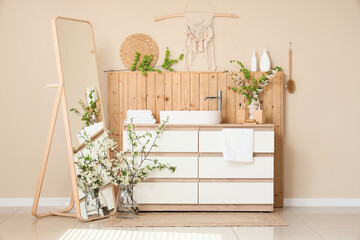 Interior of bathroom with sink, blossoming branches and mirror