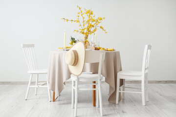 Elegant table setting with burning candles, glasses and blooming tree branches