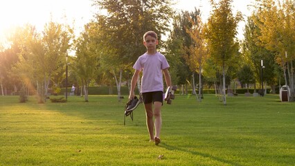 Active boy enjoying freedom summer park with skateboard. Childhood outdoor joy meets energetic street play. Pure happiness of unstructured playtime in nature. Active child walking green park