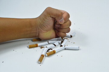 Stop smoking, Quit smoking for health
A human fist crushes several cigarettes on a clean white surface, resulting in scattered tobacco fragments and pieces. World No Tobacco Day

