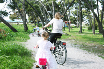 cute mother with children riding on bicycles on sea side, lifestyle people concept