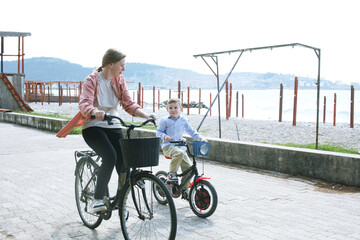 cute mother with children riding on bicycles on sea side, lifestyle people