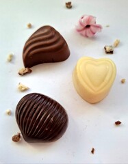 heart-shaped chocolate candy.
close-up of three chocolate candies  made of white, milk and dark chocolate on a white background