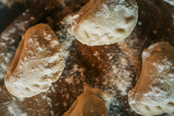 Close-up of raw handmade dumplings on a wooden board dusted with flour, ready to cook