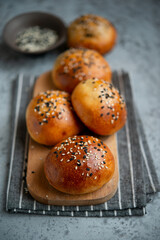Yeast dough pies with sesame seeds on a wooden board