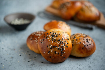 Yeast dough pies with sesame seeds on a wooden board