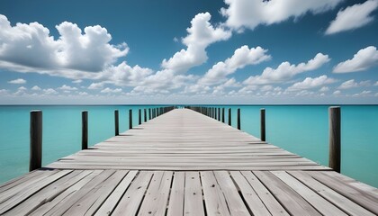 A long wooden pier stretches out over calm turquoise waters under a bright, cloudy blue sky.