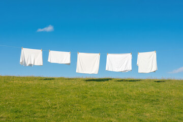 Five white sheets hang gracefully on a clothesline against a bright blue sky, evoking a sense of calm.