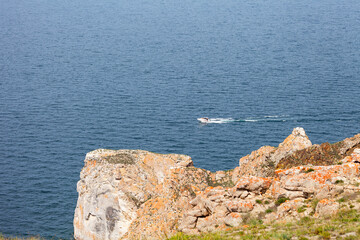 Baikal Lake on summer day. Tourists travel along Small Sea near Olkhon Island and sail past cape Sagan-Khushun or Three Brothers on motor-boat. Summer travel, adventure and outdoor recreation