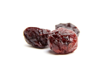 Trio of dried cranberries on a clean white surface, with glossy, wrinkled skin and deep red tones showcasing texture and natural detail