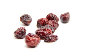 A group of dried cranberries randomly arranged on a white surface, featuring varied shapes, deep red hues, glossy skins, and wrinkled textures