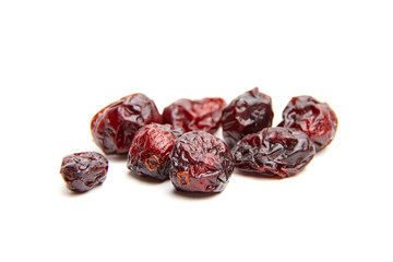 A scattered arrangement of dried cranberries on a white background, showcasing wrinkled textures,...