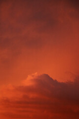 Vivid sunset sky filled with warm orange tones and layered clouds softly illuminated by the setting sun, creating a dreamy atmospheric background