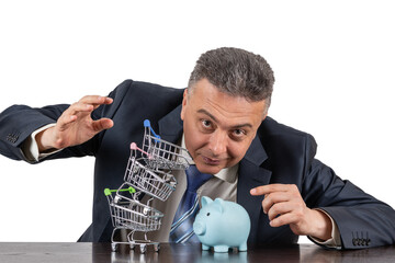 A middle-aged man in a business suit, piggy bnk  and a pyramid of empty miniature supermarket...