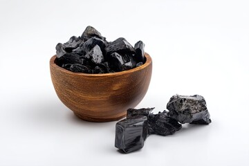 Solid shilajit resin chunks displayed in a wooden bowl on a clean white background showcasing natural texture and details