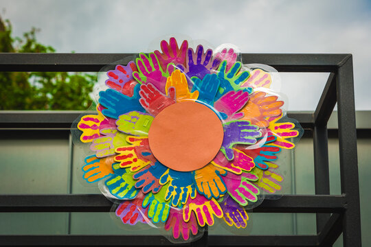 Colorful display of handprints creates a vibrant community artwork against a cloudy sky backdrop
