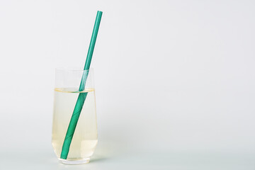 Refreshing beverage in a clear glass with a sparkling green paper straw on a clean white background. Copy space for brand advertisement text