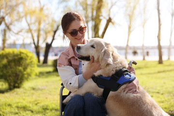 Woman in wheelchair hugging her service dog at park