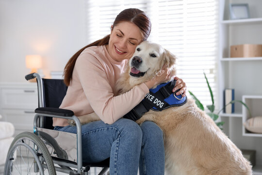 Woman in wheelchair hugging her service dog at home