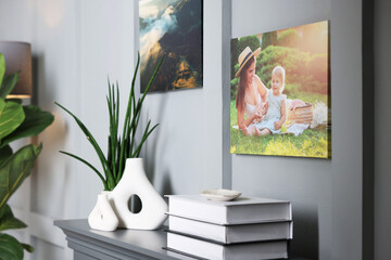 Canvas with printed photos on wall over decorative fireplace indoors