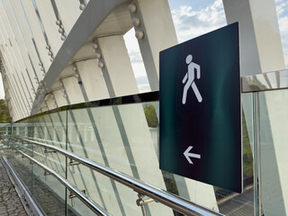 Modern architectural details of a pedestrian bridge featuring sleek glass panels, steel beams, and...