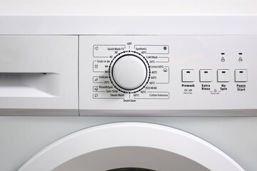 Front view of the control panel and drum conteiner of a modern washing machine white color.
