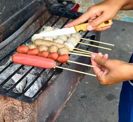 Grilling Fresh Skewers of Sausages and Meatballs Over Hot Charcoal on an Outdoor Barbecue Grill