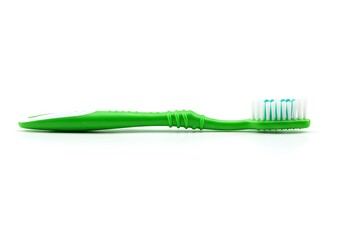 A green toothbrush with white and blue bristles lying on a white surface in a horizontal view