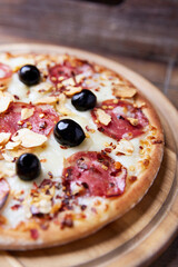 Pizza with salami and mozzarella cheese. Wooden background. Soft focus. Close up.	