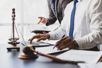 Online legal consulting concept. Lawyers collaborating on case using law book and laptop at desk,...