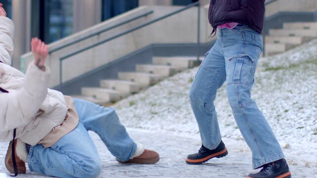 Someone slips on slippery snow as another person walks by, unaware of the humorous incident