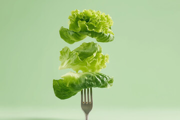 Floating lettuce leaves on a fork against a light green background showcasing healthy eating and culinary creativity