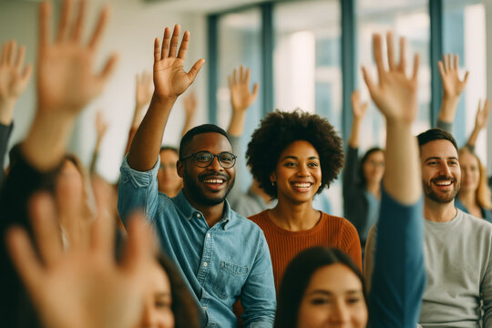 Engaged audience of young diverse adults raising hands in a seminar or classroom setting, showing enthusiasm, participation, and collaboration
